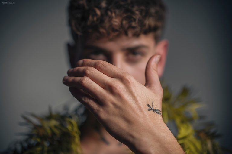 Male model with curly hair, hand in front of face, fashion shoot